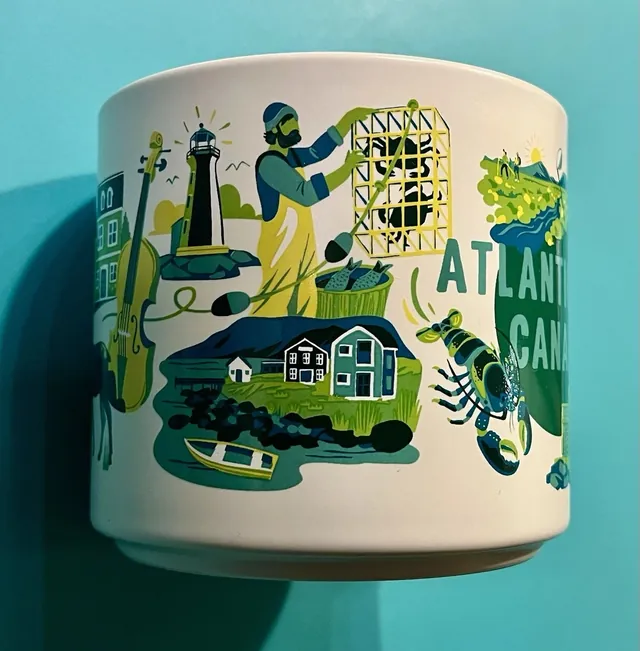 Starbucks Discovery Series Atlantic Canada mug with a lobster, a lobster trap and a golfer around the words ATLANTIC CANADA — side view