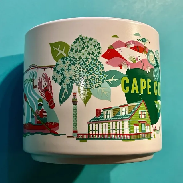 Starbucks Discovery Series Cape Cod mug with a green shingled house, hydrangeas, oysters and a gull around the words CAPE COD — side view
