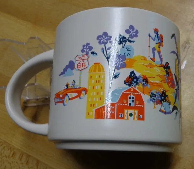 Starbucks Discovery Series Illinois mug with pumpkins, an orange fish, a deer at an easel and a canoe around the word ILLINOIS — back view