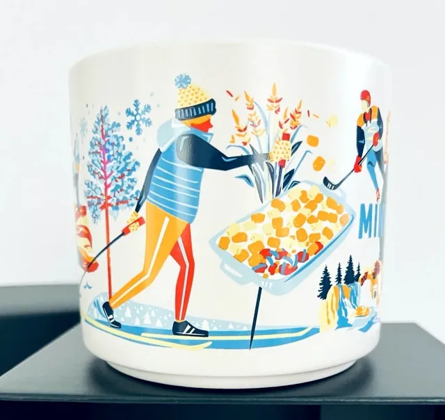 Starbucks Discovery Series Minnesota mug with a lift bridge, hockey player, apples and a skier around the word MINNESOTA — side view