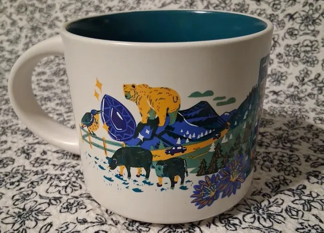 Starbucks Discovery Series Montana mug with huckleberries, an eagle, a lake, a campfire and mountains around the word MONTANA — back view
