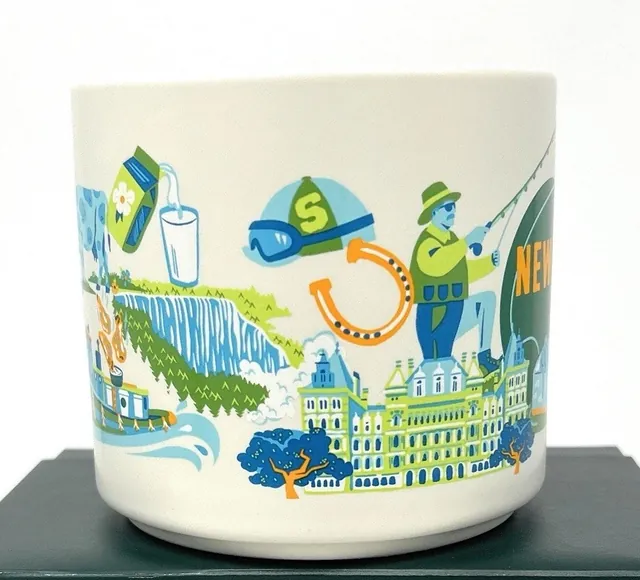 Starbucks Discovery Series New York mug with blue roses, a cake slice, a fish and a chair around the words NEW YORK — side view