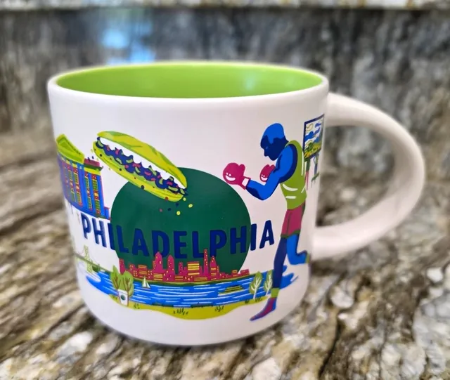 Starbucks Discovery Series Philadelphia mug with a loaded sandwich, a boxer in pink gloves and a pink skyline around the word PHILADELPHIA