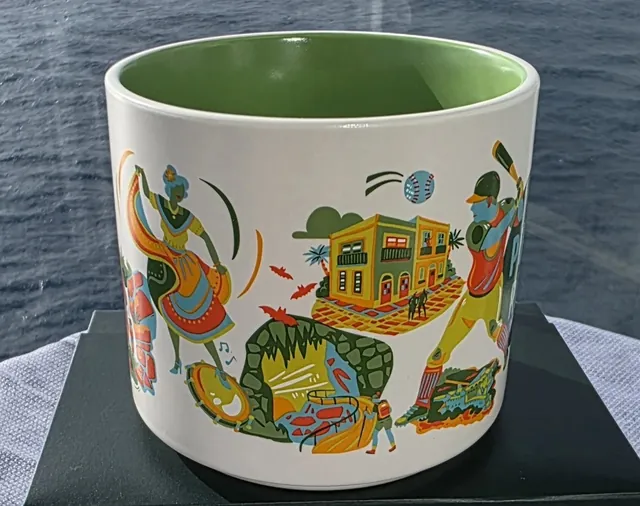 Starbucks Discovery Series Puerto Rico mug with blue PUERTO RICO lettering, a baseball batter, a parrot, a surfboard and a hibiscus flower — side view