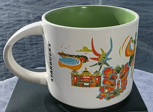 Starbucks Discovery Series Puerto Rico mug with blue PUERTO RICO lettering, a baseball batter, a parrot, a surfboard and a hibiscus flower — back view