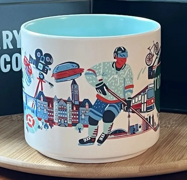 Starbucks Discovery Series Toronto mug with a bicycle, an arch bridge, a streetcar and red cliffs around the word TORONTO — side view