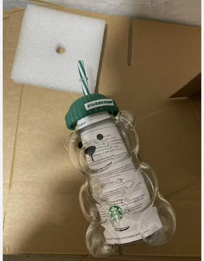 A bear cup in a shipping box, straw ring looks clear.