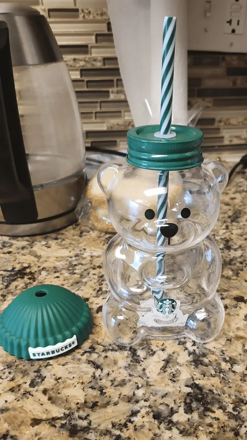A cup with its lid off beside it, on a kitchen counter, straw with ring.
