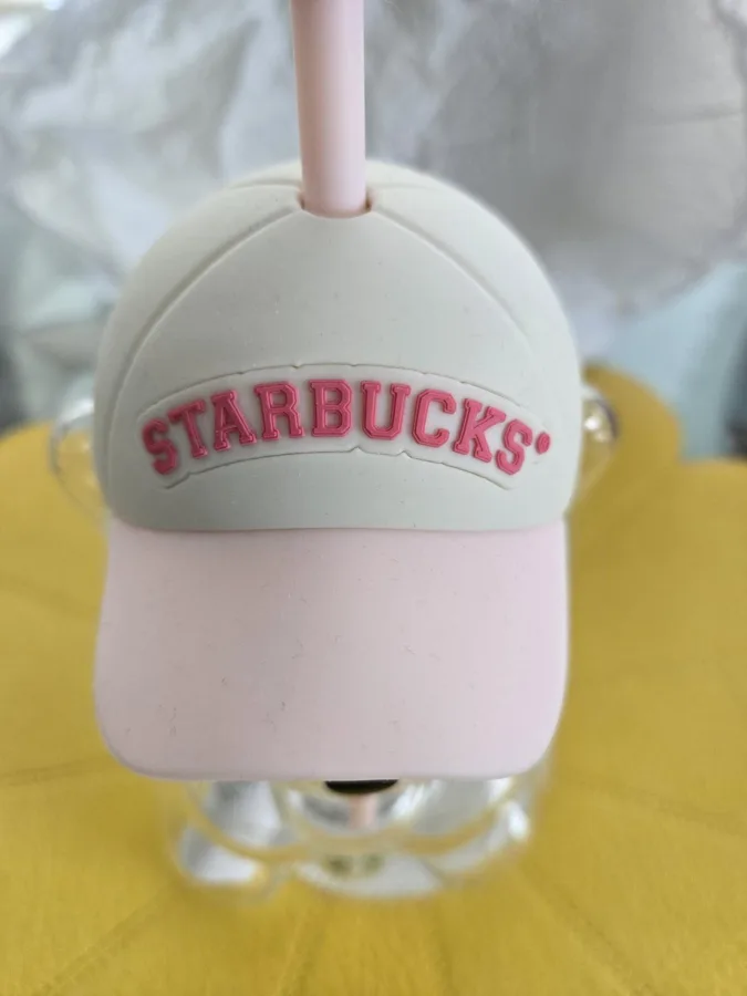 The pink cap with 'STARBUCKS®' lettering, on a yellow cloth.