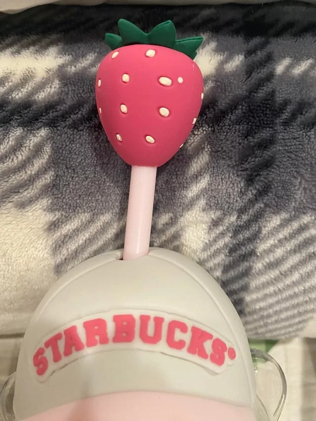 The pink cap with 'STARBUCKS®' in pink letters and the strawberry straw topper.