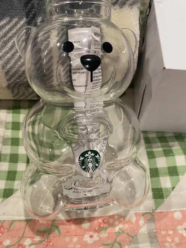 A pink-drink bear cup with its straw, in front of a white box.