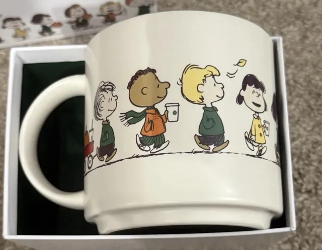 Starbucks Peanuts 14 oz ceramic mug showing the Peanuts gang with coffee cups and Snoopy asleep on a red doghouse, in its gift box, back view