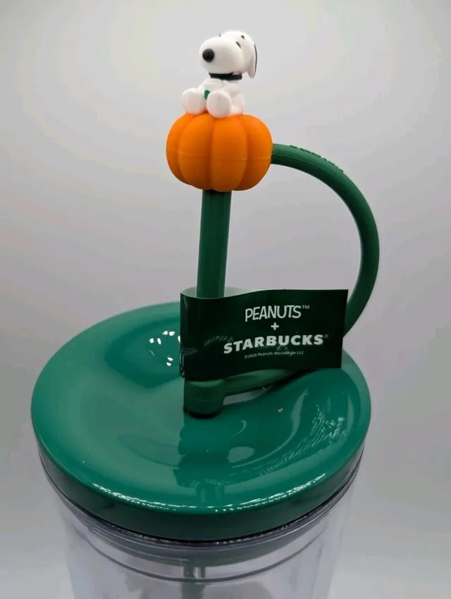 Starbucks Peanuts 24 oz clear cold cup with Charlie Brown and Linus among fall leaves and a Snoopy-on-a-pumpkin straw topper, side view