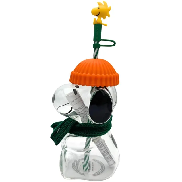 Starbucks Peanuts Snoopy glass cold cup with orange beanie lid, green scarf and Woodstock straw topper, side view