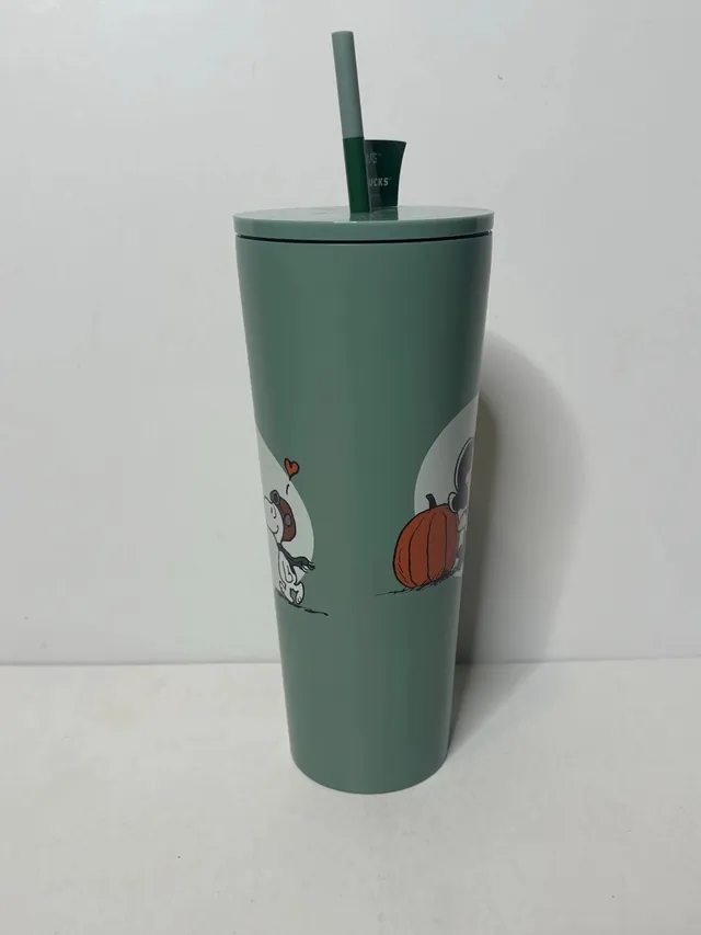 Starbucks Peanuts stainless steel cold cup in green with Lucy and Snoopy art and a PEANUTS + STARBUCKS hang tag on the straw, side view