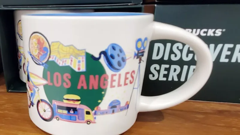 Los Angeles-themed Starbucks mug with illustrations of the Santa Monica Pier, film reel, food truck, palm trees, and a cyclist carrying a surfboard