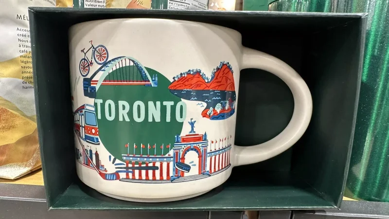 Toronto Starbucks mug with images of a streetcar, bridge, Canadian flags, and urban landscape.