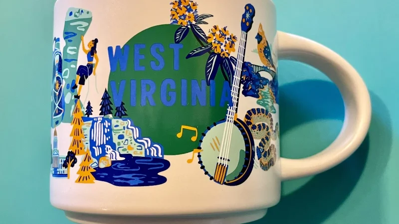 West Virginia Starbucks mug displaying a banjo, mountains, rock climbing, and bear with pancakes.