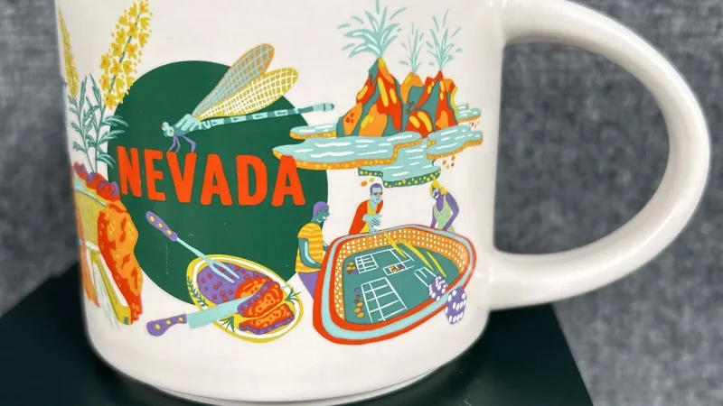 Starbucks Discovery Series mug featuring a dragonfly, Nevada desert plants, casino table, geyser, red horse, and volcanic formations representing Nevada's culture and landscape.