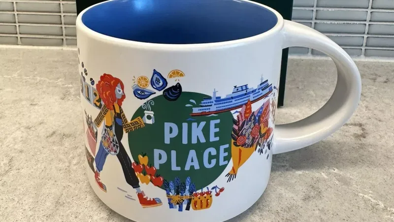 Starbucks Discovery Series mug featuring Pike Place Market design with images of seafood, flowers, a guitar, baked goods, and the year 1912.