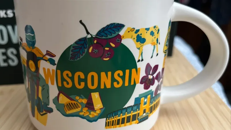 Wisconsin Discovery series mug featuring illustrations of state symbols like cheese, a motorcyclist, a cow, the state capitol, and cherry blossoms