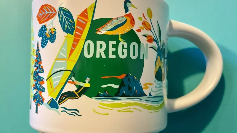 Oregon Starbucks mug displaying a windsurfer, duck, Bigfoot, pine trees, and woodland creatures.