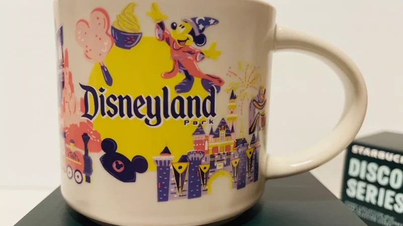 Disneyland Park Starbucks mug with illustrations of Mickey Mouse, the castle, fireworks, and Disney-themed attractions.