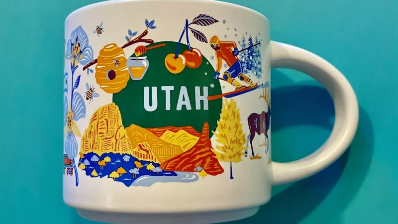 Utah Starbucks mug with images of a beehive, skier, red rock formations, and cactus.