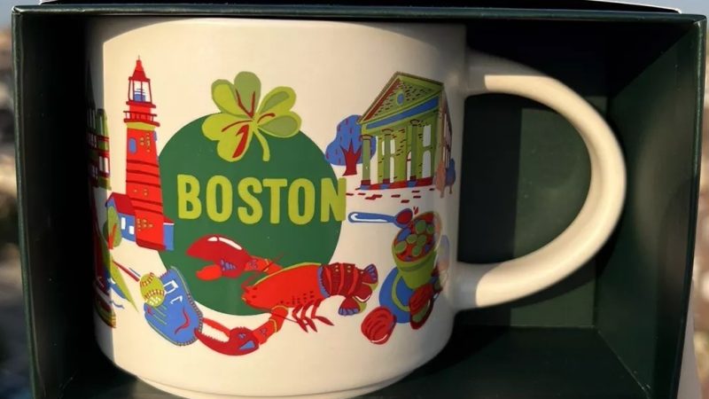 Boston Starbucks mug with illustrations of a red lighthouse, lobster, four-leaf clover, historic sites, and musical performance elements.