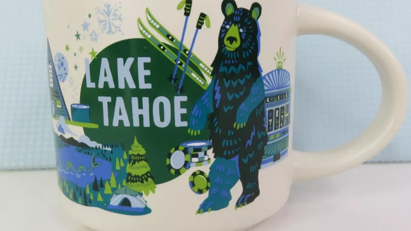 Lake Tahoe Starbucks mug with a bear, ski poles, slot machine, campsite, and lake illustration.