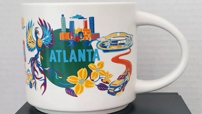 Atlanta Starbucks mug featuring downtown skyline, Mercedes-Benz Stadium, a phoenix, Peachtree Street sign, and Southern culinary items.