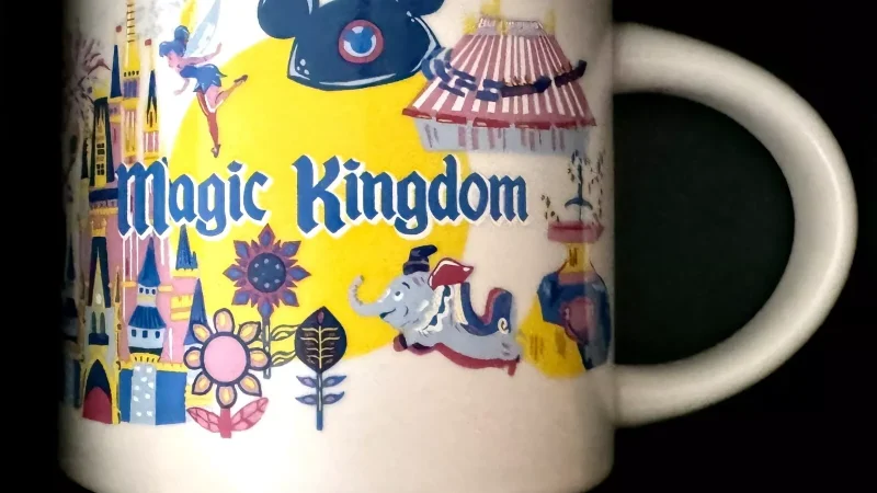 Magic Kingdom Starbucks mug with images of Cinderella's Castle, Dumbo, mouse ears, and amusement rides.